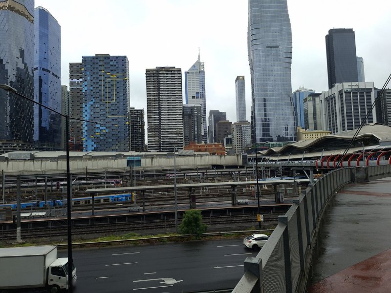 Melbourne towers above the railway yards and a wet footbridge