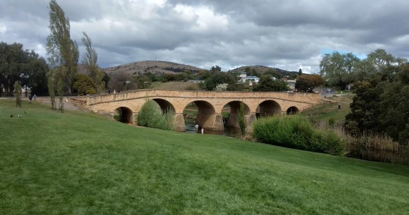 Richmond Bridge, a stone arch bridge, across a grassy riverbank